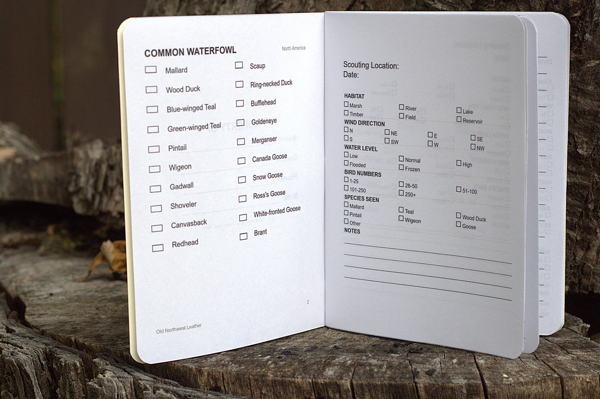An open pocket notebook showing printed checklists and notes pages, photographed standing on a weathered wooden log outdoors.